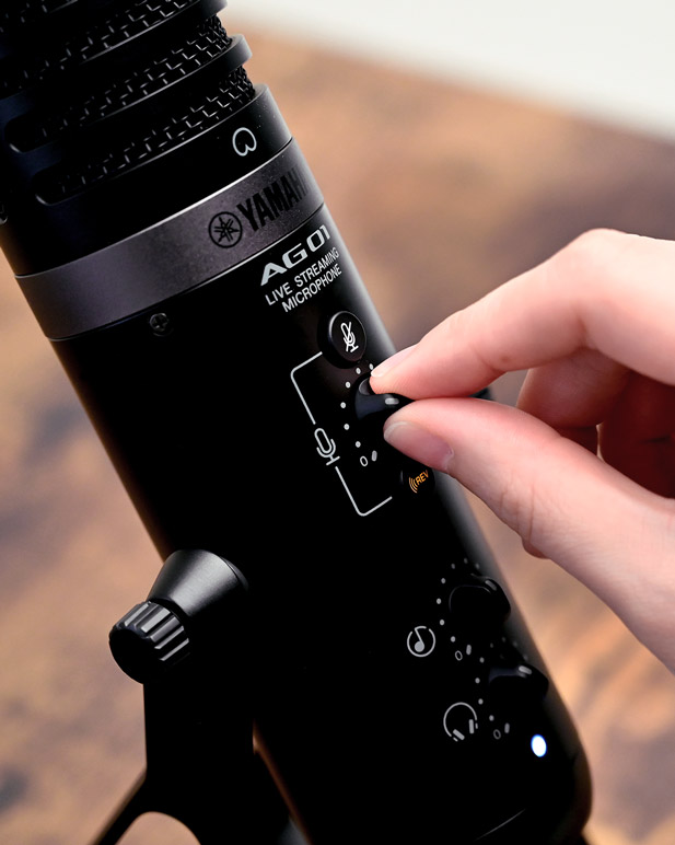 Person adjusting volume on the Yamaha AG01 microphone.