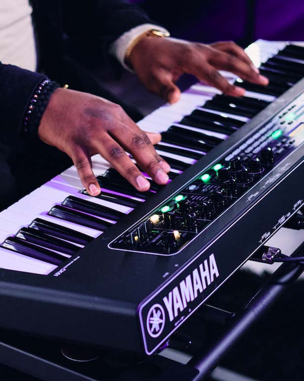 Closeup of person playing a Yamaha synthesizer.