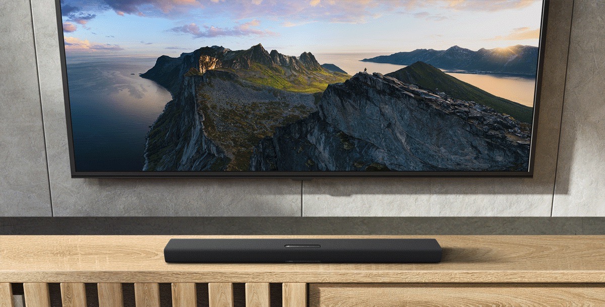 Image of sound bar on a wooden console in front of TV.
