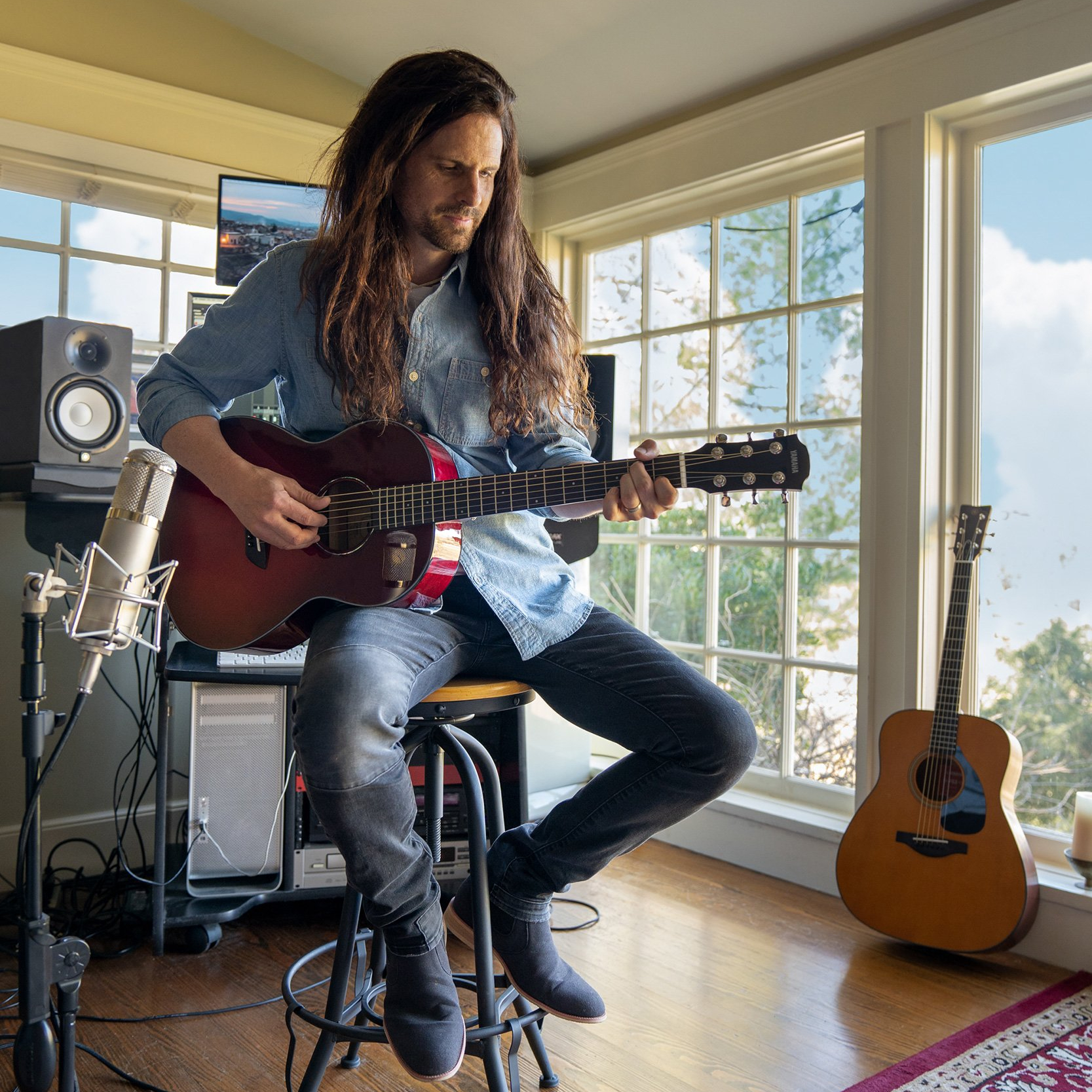 Person playing guitar inside a home studio.